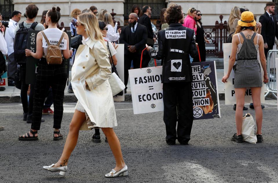 An attendee of Victoria Beckham's fashion show walks past Extinction Rebellion protestors as they demonstrate against London Fashion Week at the Foreign and Commonwealth office in London. (REUTERS)