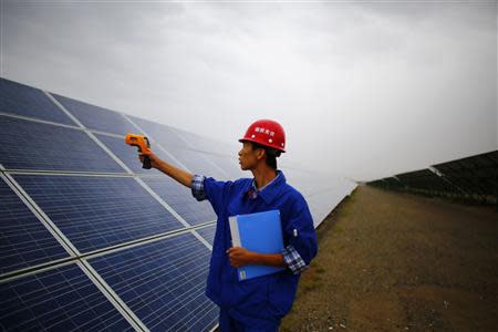 A worker inspects solar panels at a solar farm in Dunhuang, 950km (590 miles) northwest of Lanzhou, Gansu Province September 16, 2013. REUTERS/Carlos Barria