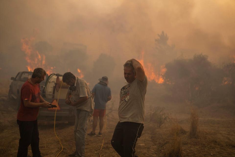 Locals try to extinguish a wildfire burning in Gennadi village on the Aegean Sea island of Rhodes on Tuesday (AP)