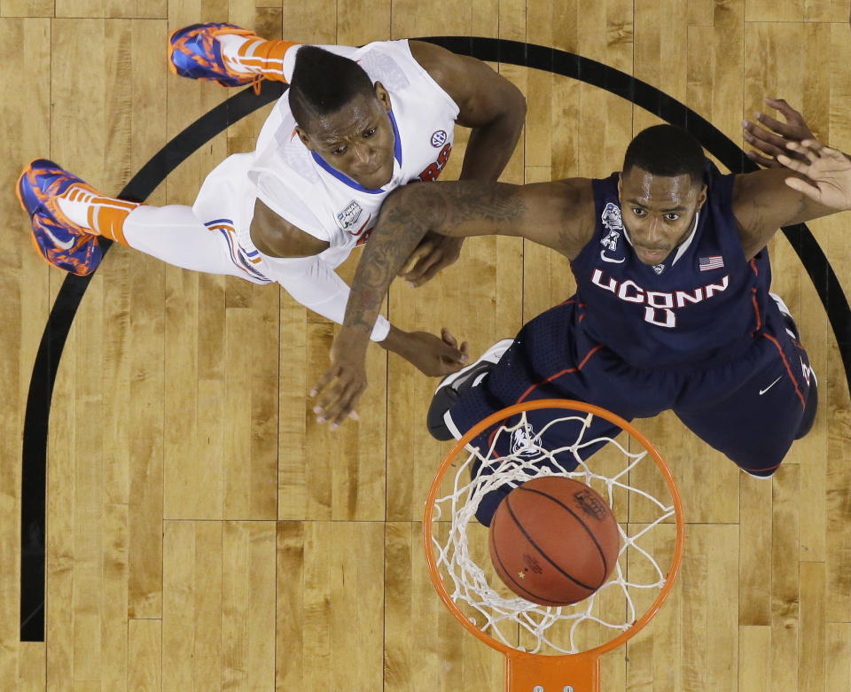 Florida forward Will Yeguete, left, and Connecticut forward Phillip Nolan, right, eye a made basket during the first half of an NCAA Final Four tournament college basketball semifinal game Saturday, April 5, 2014, in Arlington, Texas. (AP Photo/David J. Phillip)