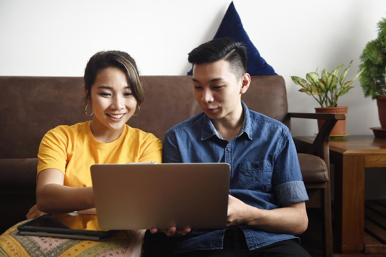 Young couple sitting in the floor reading from a laptop