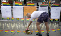 <p>Rickey Swanson arranges a bouquet of flowers at a memorial with 50 candles for at least 50 people gunned down at a gay nightclub in Orlando, Fla., during the Gay Pride Parade in West Hollywood, June 12, 2016. (Mindy Schauer/The Orange County Register via AP) </p>