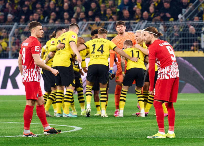 Borussia Dortmund's players form a circle around goalkeeper Gregor Kobel next to Freiburg's Maximilian Eggestein (L) and Lucas Hoeler (R) during the German Bundesliga soccer match between Borussia Dortmund and SC Freiburg at the Signal Iduna Park. Bernd Thissen/dpa