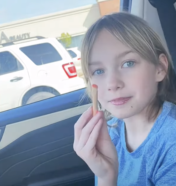Young girl in a car holding a makeup applicator