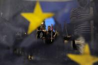 Anti-EU protesters are seen through a burned and torn European Union flag during a protest at the northern city of Thessaloniki, Greece July 1, 2015. REUTERS/Alexandros Avramidis