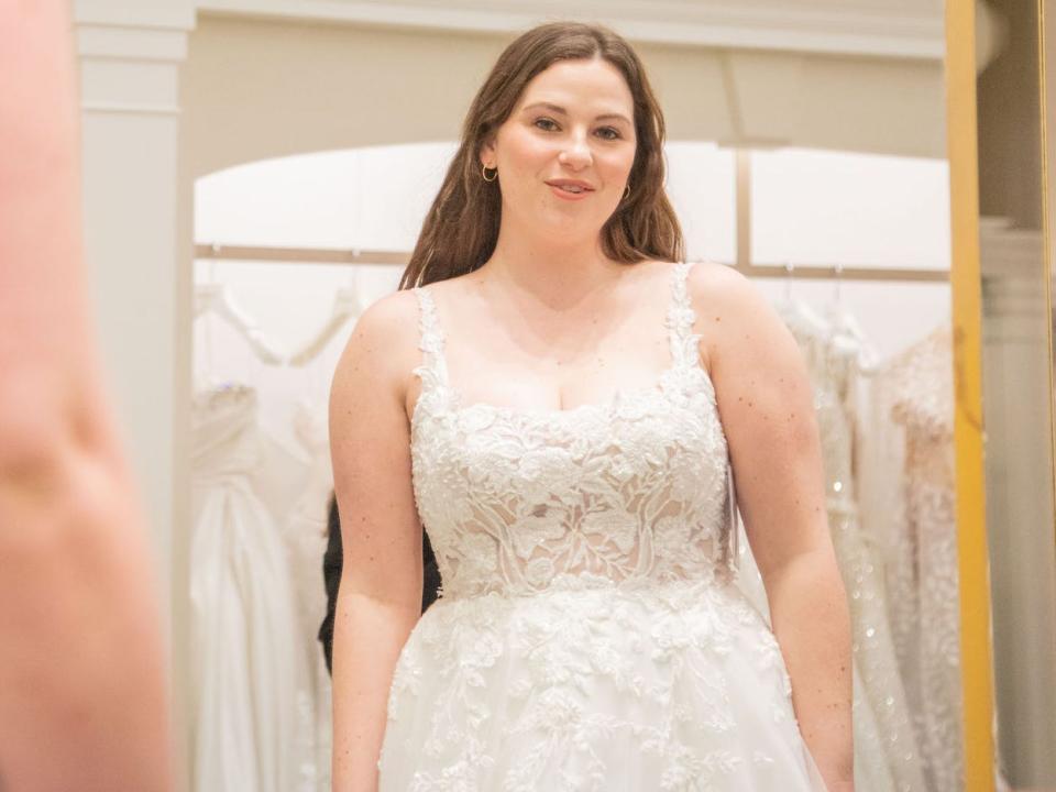 A woman looks at herself in a mirror in a wedding dress.