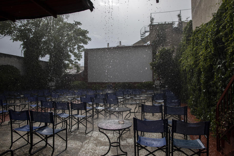 In this Wednesday, June 3, 2020 photo, an afternoon downpour hits the Zephyros open-air cinema that specializes in films from past decades in the Petralona district in central Athens. (AP Photo/Petros Giannakouris)