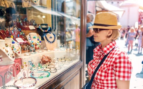 A woman in a straw hat looking at Murano glass jewellery - Credit: Getty