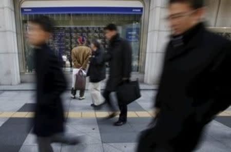 A pedestrian looks at various stock prices outside a brokerage in Tokyo, Japan, February 26, 2016. REUTERS/Yuya Shino