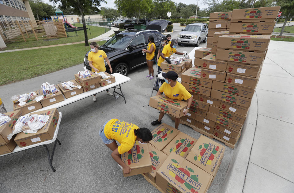 Volunteers load groceries into cars during a food distribution event, Tuesday, July 21, 2020, at St. Monica's Catholic Church in Miami Gardens, Fla. (AP Photo/Wilfredo Lee)
