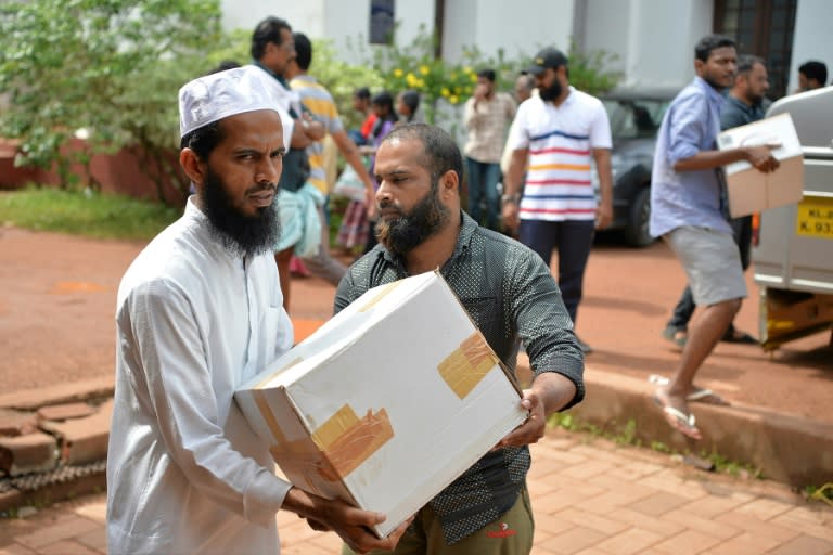 Volunteers carry boxes of food aid at a relief camp for families displaced by flooding in Aluva on the outskirts of Kochi