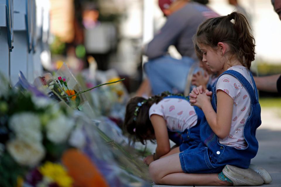 A young girl prays in front of a memorial site.