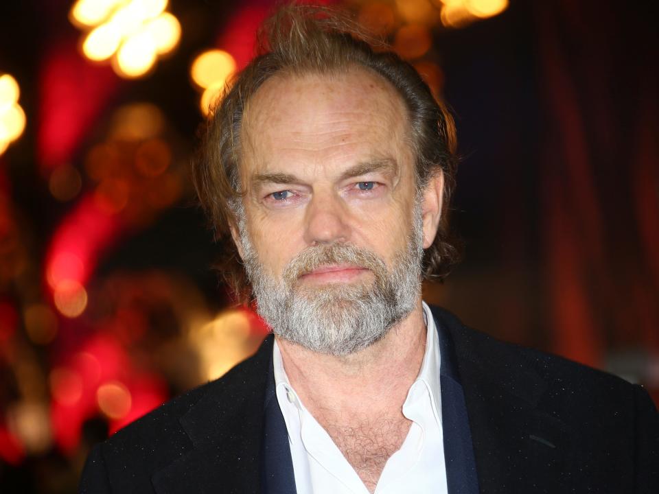 hugo weaving wearing a black suit and white button up