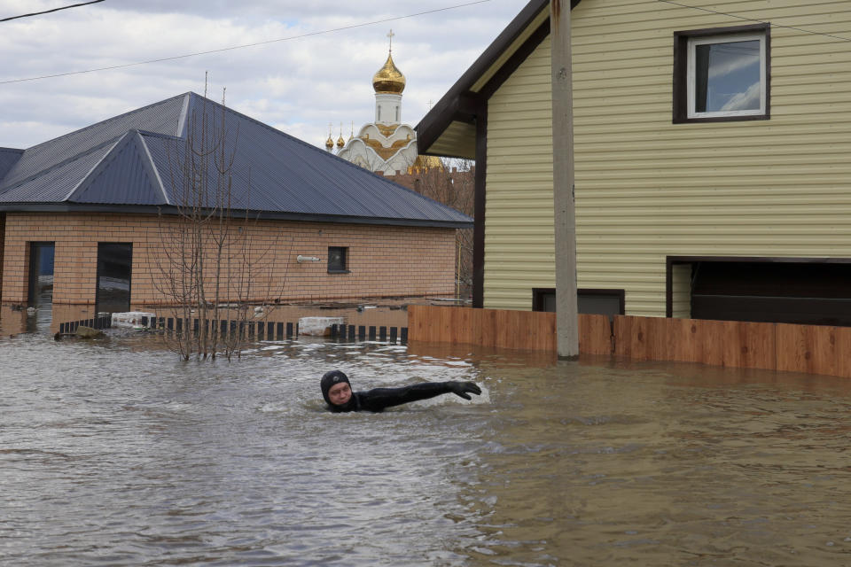 A local resident swims in the flooded street between houses in Orenburg, Russia, on Saturday, April 13, 2024. Over 11,700 houses remain flooded in the Orenburg region and some 10,700 people have already been evacuated from flooded areas. The deluge hit the region after a dam on the Ural River burst last week under surging waters. (AP Photo/Vitaly Smolnikov)