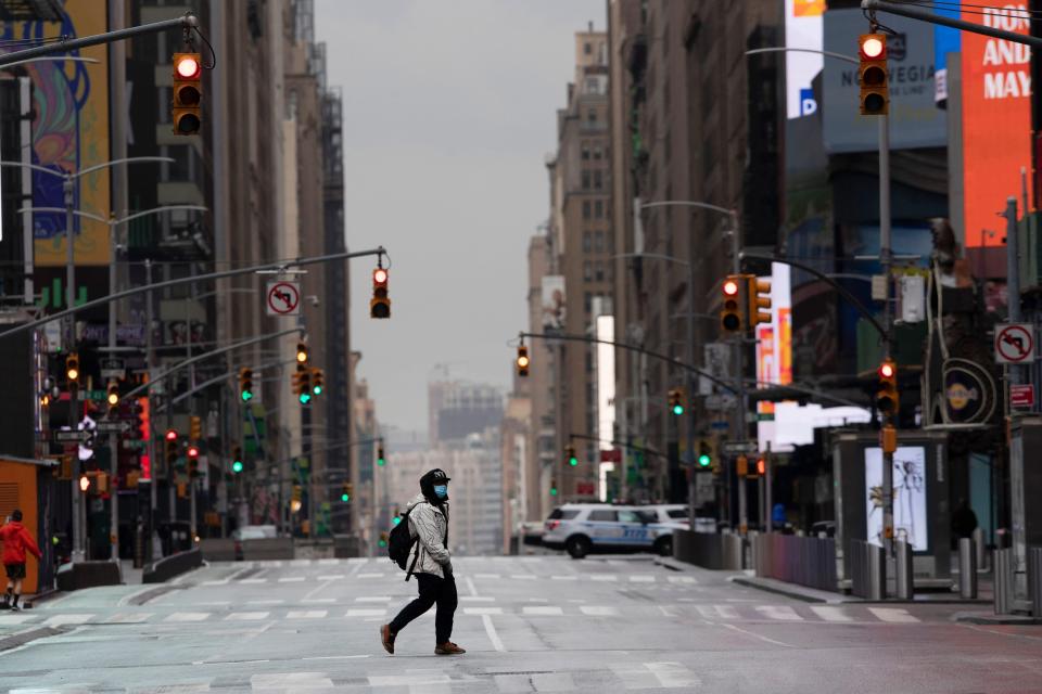 A man wearing a mask crosses the street in a quiet Times Square, Thursday, April 9, 2020, during the coronavirus epidemic in New York City.