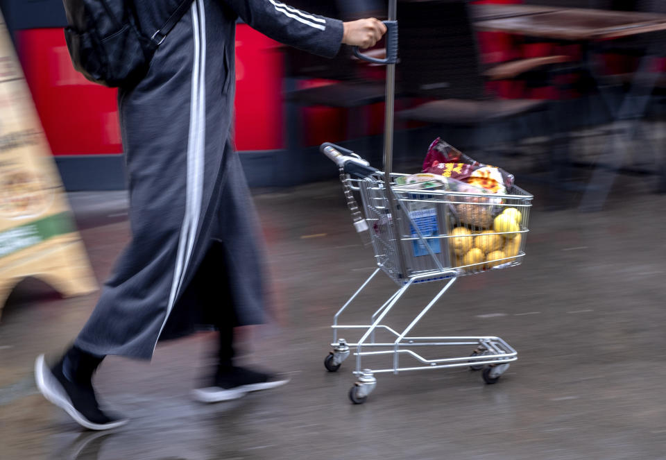 FILE - A woman pushes a small shopping cart outside a discount market in Frankfurt, Germany, Thursday, July 27, 2023. Germany's economy is likely to shrink again slightly in the current fourth quarter, the country's central bank said Monday, while a survey showed business confidence in Europe's biggest economy retreating unexpectedly. (AP Photo/Michael Probst, File)