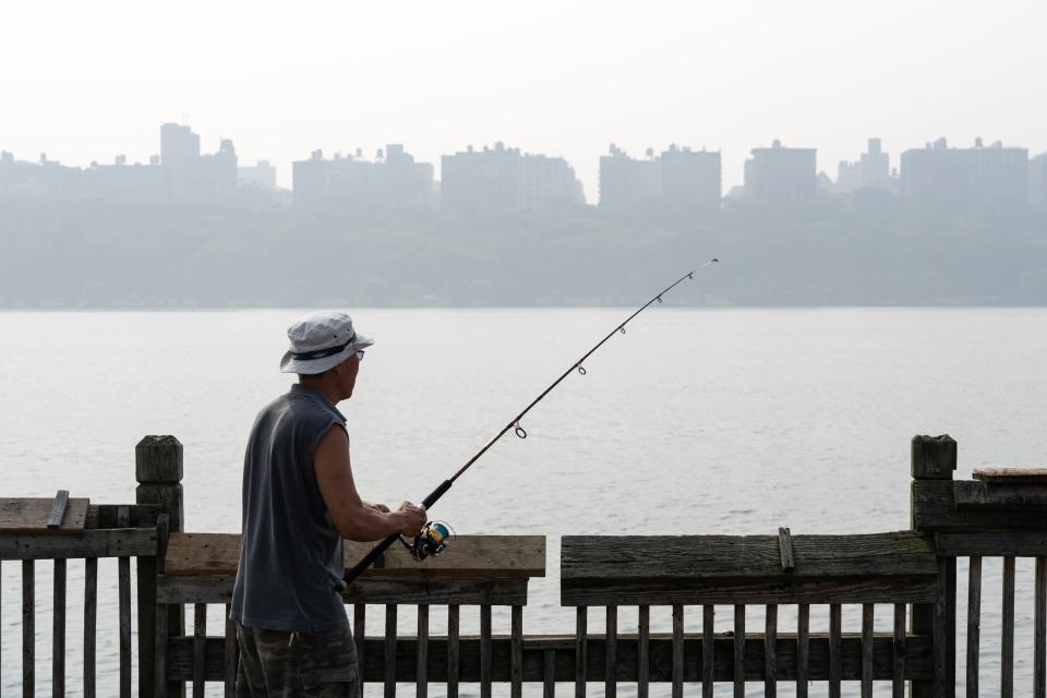 John Lee, of Cliffside Park, fishes in the Hudson River with New York City obscured due to the the poor air quality in Edgewater, NJ on Friday June 30, 2023.