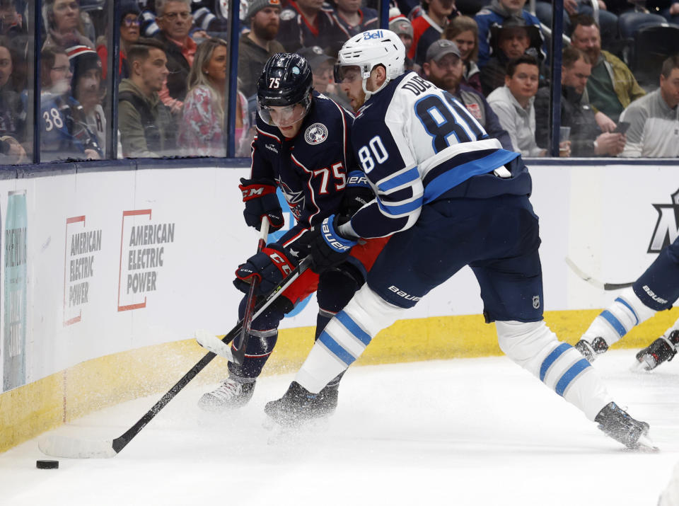 Winnipeg Jets forward Pierre-Luc Dubois, right, passes the puck in front of Columbus Blue Jackets defenseman Tim Berni during the first period of an NHL hockey game in Columbus, Ohio, Thursday, Feb. 16, 2023. (AP Photo/Paul Vernon)