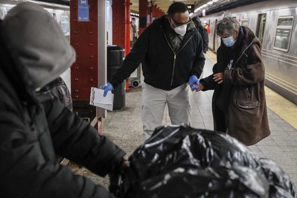 A homeless man is given assistance by a homeless outreach worker in the 207th Street station for the A train, Thursday, April 30, 2020, in the Manhattan borough of New York. The United Nation's independent expert on poverty is warning that the worst impacts from the coronavirus pandemic on poverty are yet to come, and that measures taken by governments to protect societies are insufficient. (AP Photo/John Minchillo)