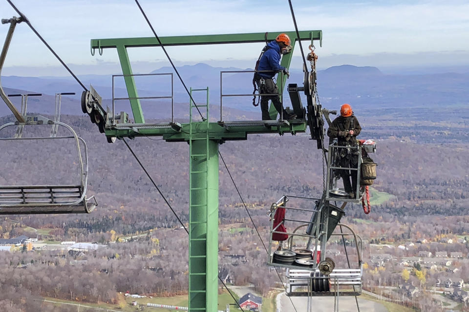 Workers do routine seasonal maintenance to a chairlift, Wednesday, Oct. 27, 2021, at Jay Peak Resort, in Jay, Vt., ahead of the upcoming season. After the previous season with mask mandates and other virus-related restrictions ski resorts are expecting a more normal season this winter. (AP Photo/Lisa Rathke)