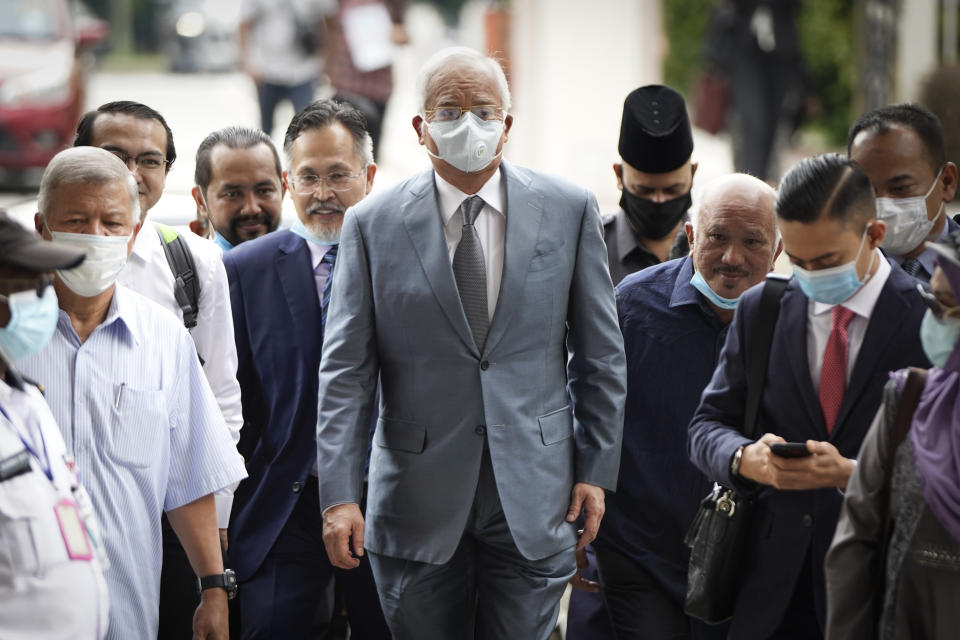 Former Malaysian Prime Minister Najib Razak, center, wearing a face mask walks toward court house in Kuala Lumpur, Malaysia, Thursday, June 4, 2020. Closing arguments are expected in the first corruption trial of him linked to the multibillion-dollar looting of the 1MDB state investment fund. (AP Photo/Vincent Thian)