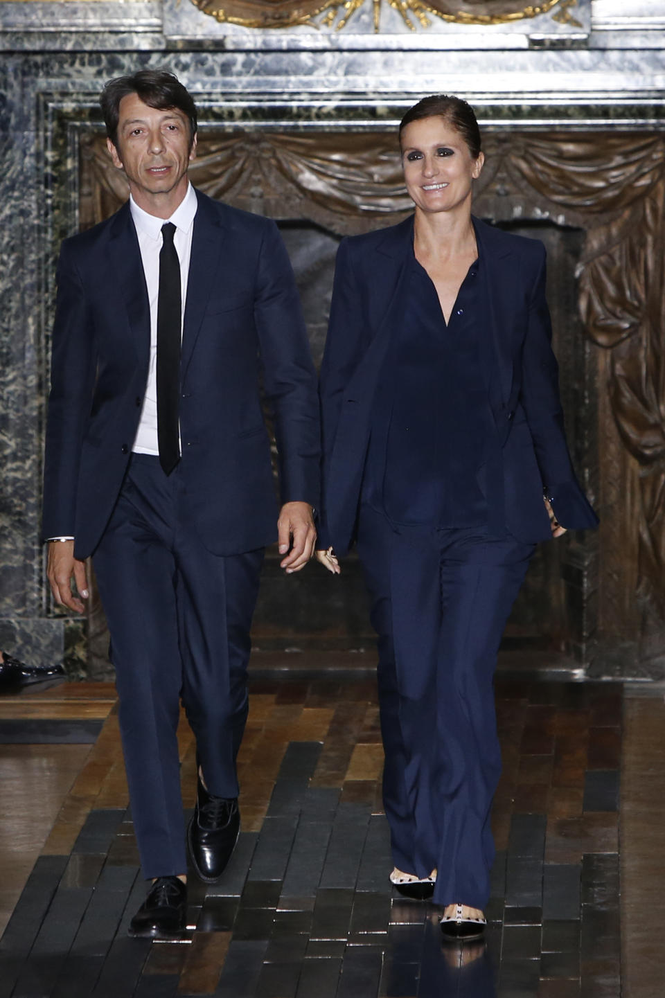 Fashion designers Maria Grazia Chiuri, right, and Pier Paolo Piccioli acknowledge applause following the presentation of the men's fashion Spring-Summer 2014 collection they designed for Valentino, Wednesday, June 26, 2013 in Paris. (AP Photo/Francois Mori)