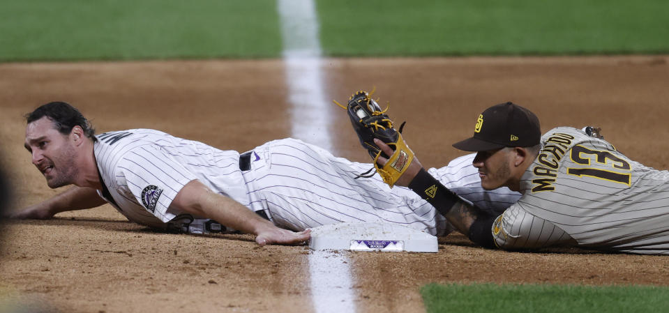 San Diego Padres third baseman Manny Machado, right, holds up his glove to show that he tagged out Colorado Rockies' Daniel Murphy as he tries to advacnce from first to third base on a single hit by Ryan McMahon in the sixth inning of a baseball game Friday, July 31, 2020, in Denver. (AP Photo/David Zalubowski)