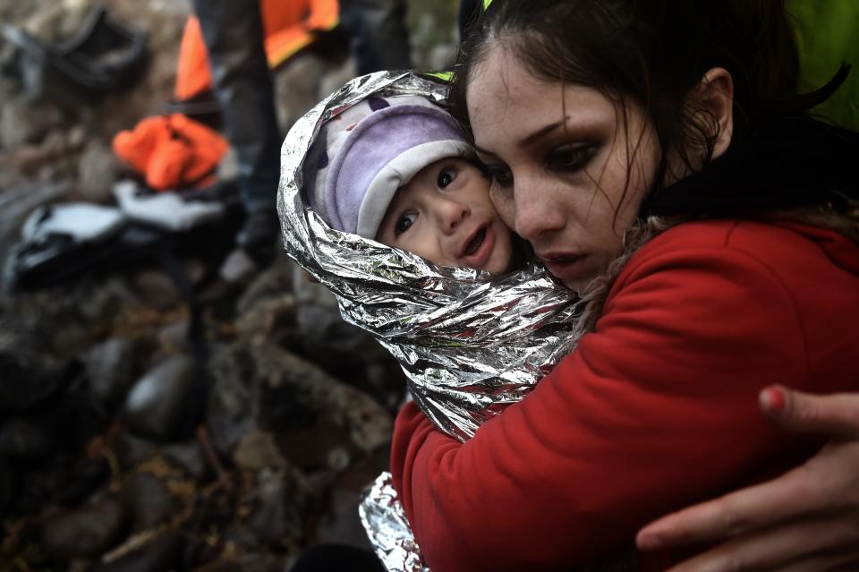 A woman hugs a baby wrapped in an emergency blanket as refugees and migrants arrive on the Greek island of Lesbos after crossing the Aegean sea from Turkey on October 1, 2015.&nbsp;