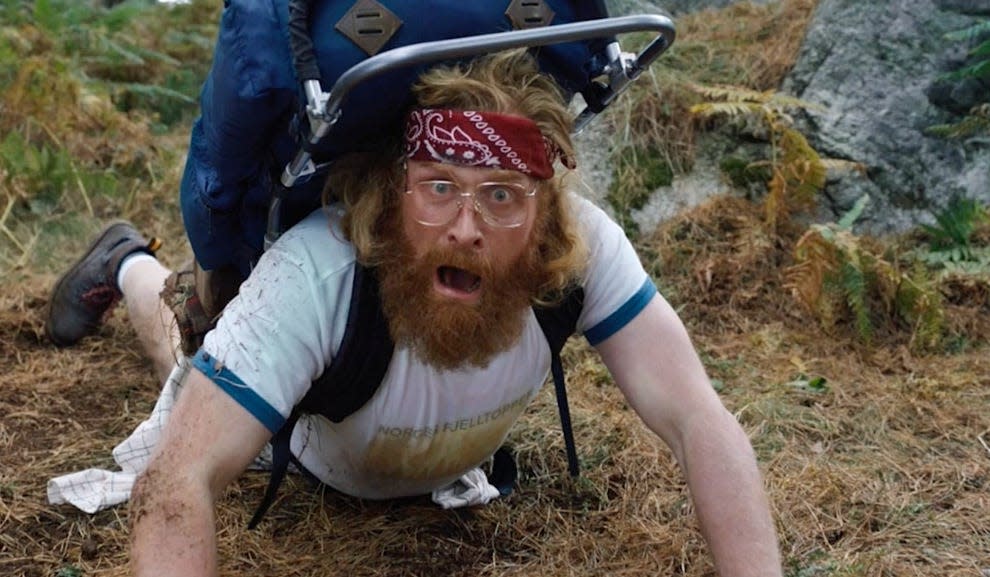 Kristofer Hivju wearing glasses and a red headband on the ground with his mouth open