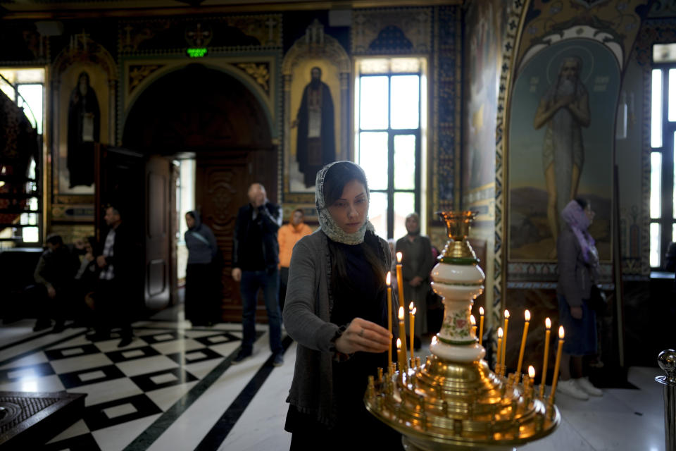 A woman lights a candle at Kyiv Pechersk Lavra Monastery in Kyiv, Ukraine, Saturday, May 28, 2022. The leaders of the Orthodox churches in Ukraine that were affiliated with the Russian Orthodox Church have announced on a statement they will sever ties with Russia over its invasion of Ukraine. (AP Photo/Natacha Pisarenko)