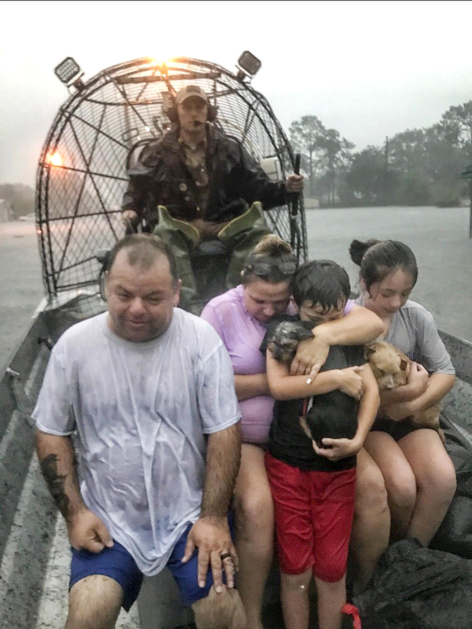 In this photo provided by the Texas Parks & Wildlife Department, a family is rescued via fan boat by a member of the department from the flood waters of Tropical Depression Imelda near Beaumont, Texas, Thursday, Sept. 19, 2019. (Texas Parks & Wildlife Department via AP)