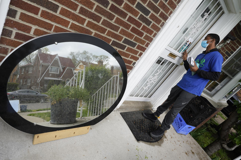 Sirgregory Allen leaves a flyer at a home in Detroit, Tuesday, May 4, 2021. Officials are walking door-to-door to encourage residents of the majority Black city to get vaccinated against COVID-19 as the city's immunization rate lags well behind the rest of Michigan and the United States. (AP Photo/Paul Sancya)