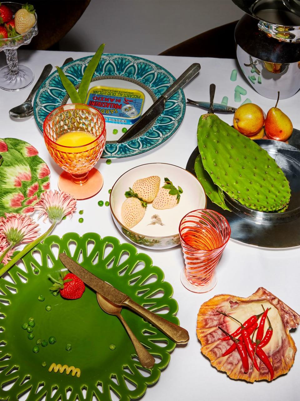 a table with plates in various colors and shapes with food and silverware and glassware