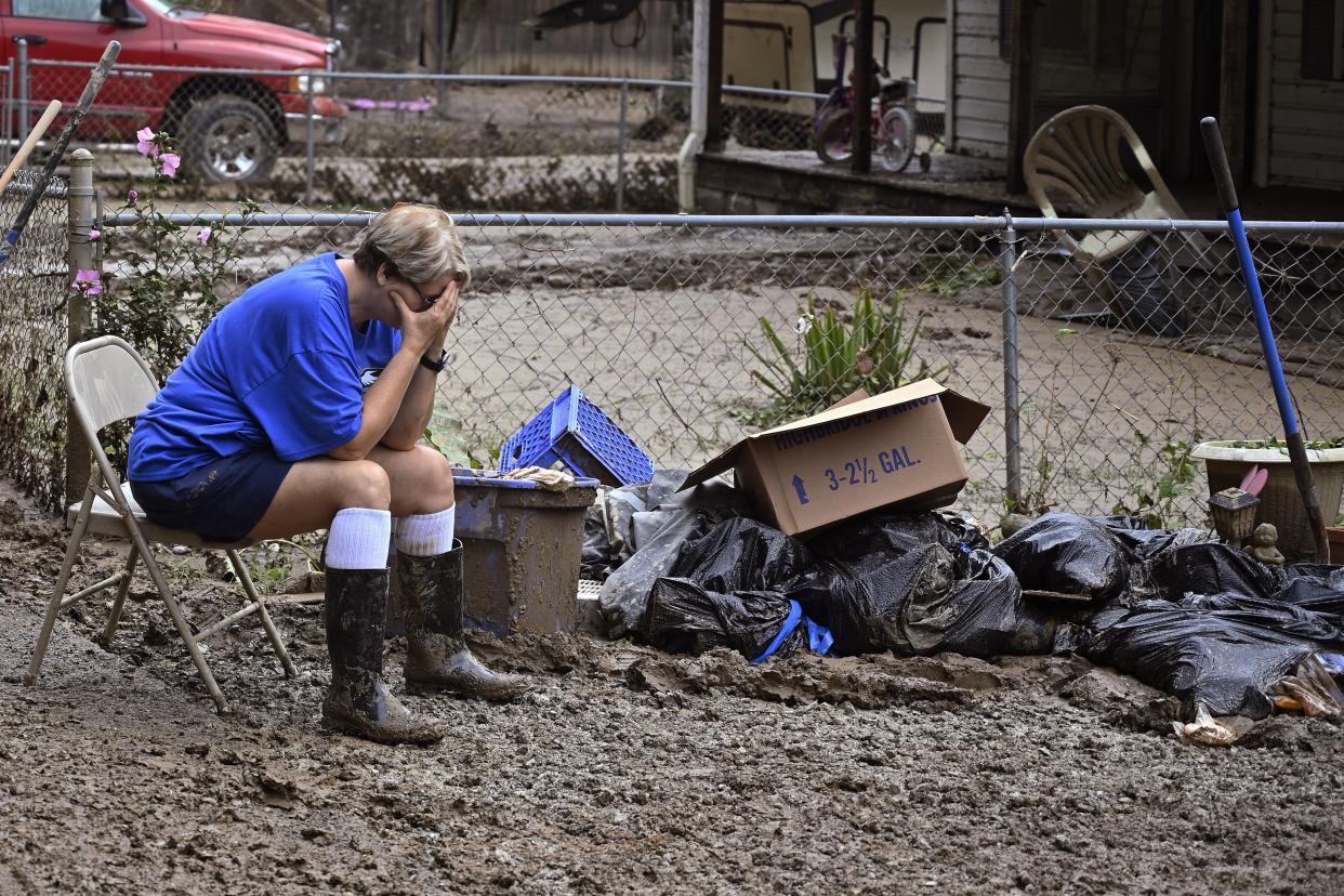 Teresa Reynolds sits exhausted as members of her community clean the debris from their flood-ravaged homes in Ogden Hollar at Hindman, Ky., Saturday, July 30, 2022. 