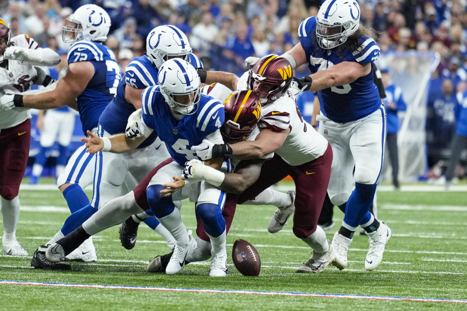 Indianapolis Colts quarterback Sam Ehlinger (4) fumbles the ball as tackled by the Washington Commanders in the first half of an NFL football game in Indianapolis, Sunday, Oct. 30, 2022. The Commanders recovered the ball. (AP Photo/AJ Mast)