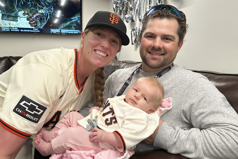 San Francisco Giants assistant coach Alyssa Nakken, left, poses for photos with her husband, Robert, and their daughter, Austyn, before a baseball game between the Giants and the San Diego Padres in San Francisco, Friday, April 5, 2024. (AP Photo/Janie McCauley)