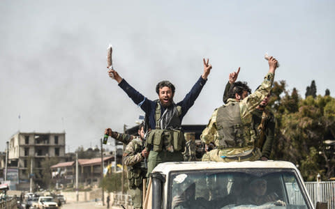 Turkish-backed Syrian Arab fighters celebrate after seizing control of the northwestern Syrian city of Afrin - Credit: BULENT KILIC/AFP/Getty Images