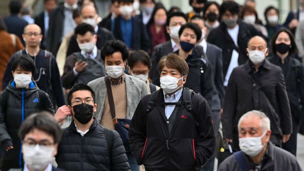 PHOTO: Commuters walk on a street in Tokyo, March 13, 2023, on the first day of reduced mask requirements. (Kazuhiro Nogi/AFP via Getty Images)