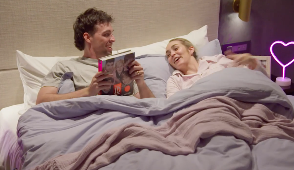 Ollie Skelton reading a One Direction book to Tahnee Cook in bed