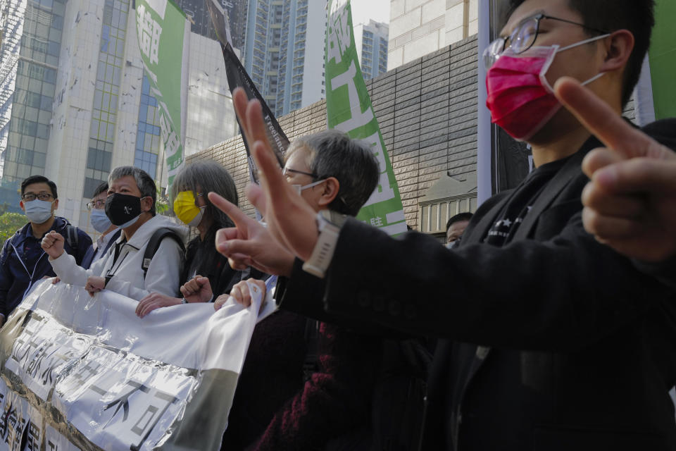 Hong Kong pro-democracy activists Lee Cheuk-yan wearing a black mask and Leung Kwok-hung wearing a yellow mask shout slogans as they arrive at a court in Hong Kong Tuesday, Feb. 16, 2021. They are among nine prominent Hong Kong's democracy advocates facing trial Tuesday on charges of organizing an unauthorized assembly in August 2019. (AP Photo/Vincent Yu)