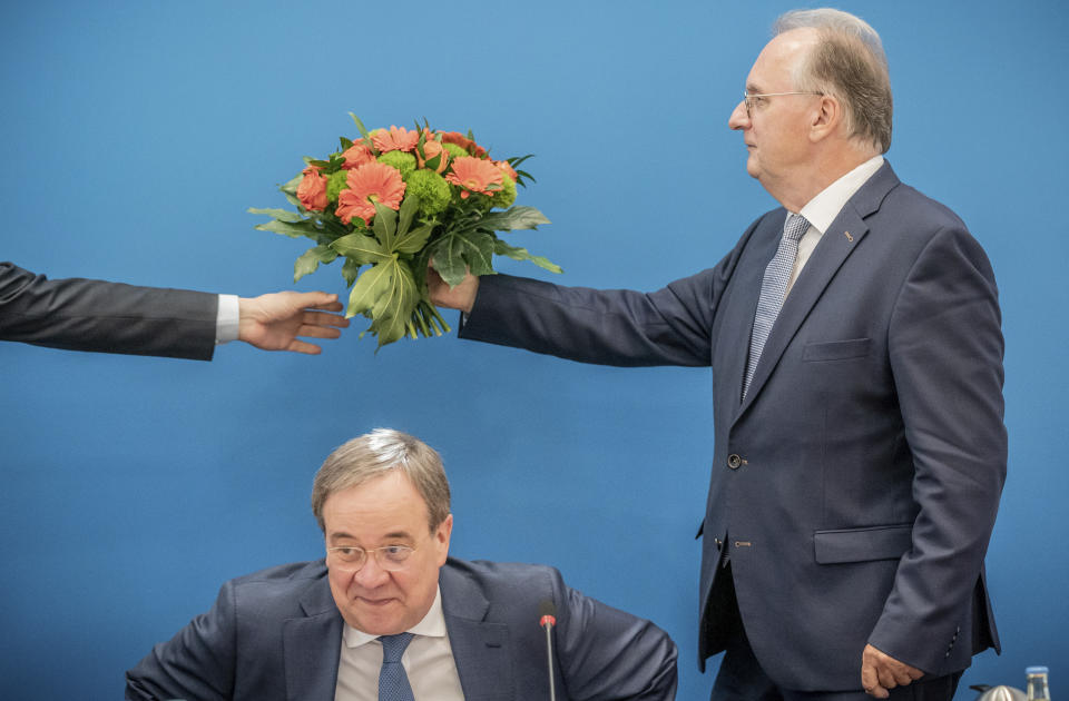 07 June 2021, Berlin: Reiner Haseloff, Minister President of Saxony-Anhalt, hands over the bouquet of flowers he received from the CDU Federal Chairman and Minister President of North Rhine-Westphalia, Armin Laschet (front), to a person before the start of the CDU Federal Executive Committee meeting in Berlin, Germany, Monday, June 7, 2021. The top bodies are discussing the results after the state elections in Saxony-Anhalt. (Michael Kappeler/Pool via AP)