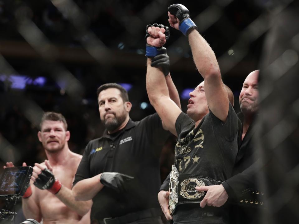 Georges St-Pierre, right, of Canada, celebrates after defeating England’s Michael Bisping, left, in a middleweight title bout at UFC 217. (AP Photo/Frank Franklin II)