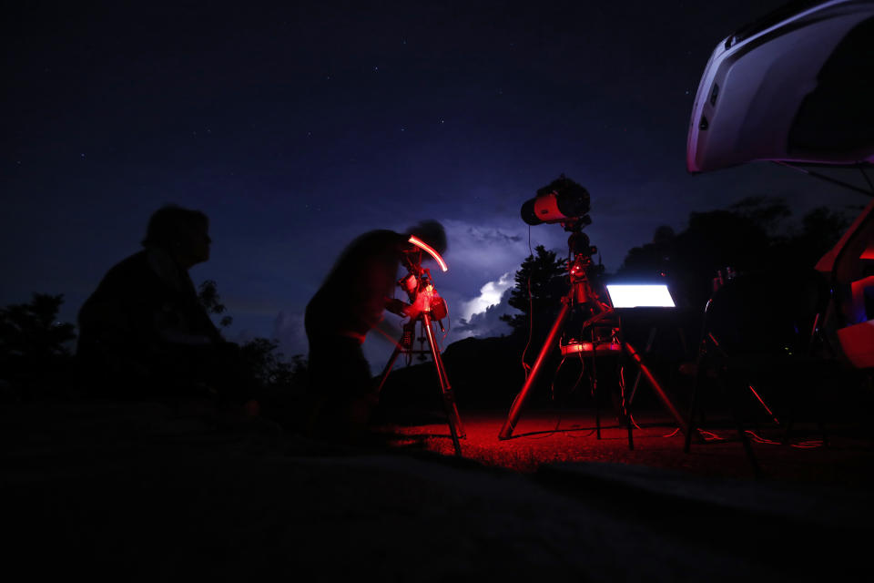 Astrophotographer Johnny Horne works under the night sky to photograph Comet NEOWISE as his wife Ann looks on at Grandfather Mountain in Linville, N.C., Friday, July 17, 2020. (AP Photo/Gerry Broome)