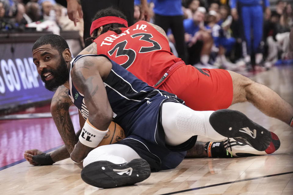 Dallas Mavericks' Kyrie Irving fights for a loose ball with Toronto Raptors' Gary Trent Jr. during the second half of an NBA basketball game in Toronto on Wednesday, Feb. 28, 2024. (Chris Young/The Canadian Press via AP)