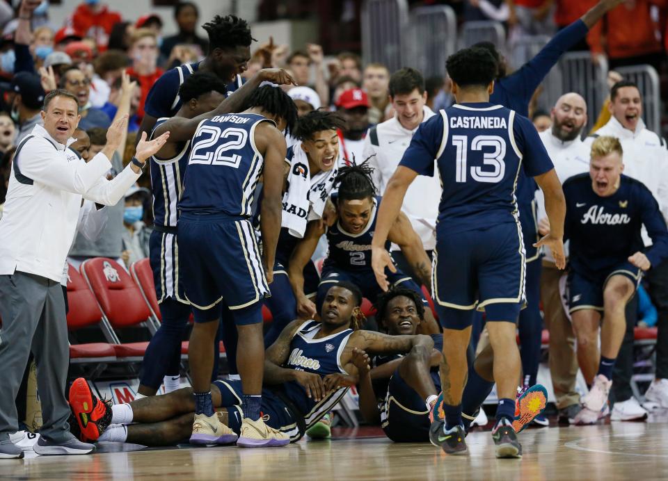 Akron Zips guard Bryan Trimble Jr. (4) falls into the bench after hitting a three pointer during the second half of the NCAA men's basketball game against the Ohio State Buckeyes at Value City Arena in Columbus on Tuesday, Nov. 9, 2021. The Buckeyes won 67-66.