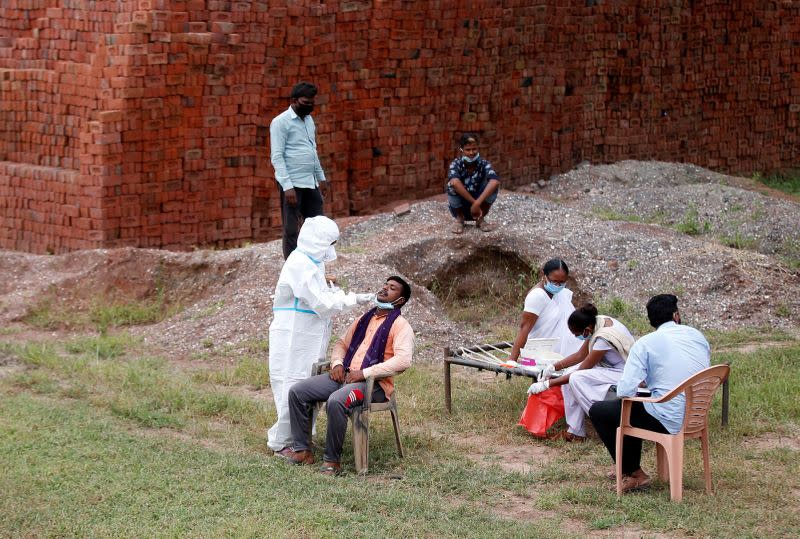 Healthcare worker wearing PPE takes swab in village Rajoda