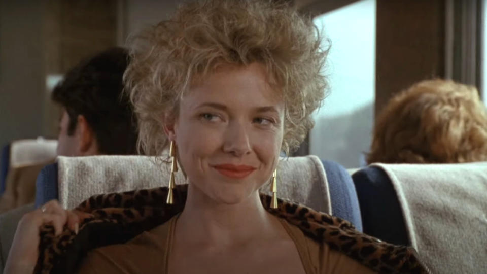 Annette Bening smiles coyly as she starts to get up from her seat in The Grifters.