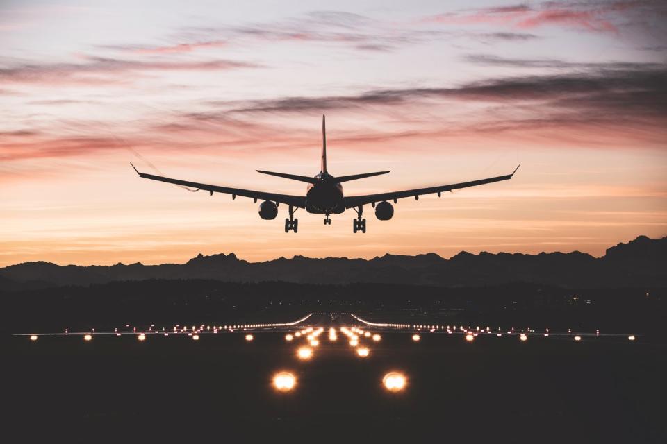 An airplane taking off and heading toward the sunset. 