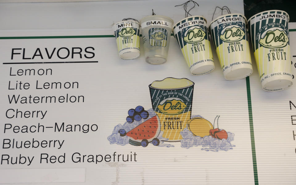 This April 30, 2014 photo shows drink containers hanging near a menu on a wall at Del's Frozen Lemonade in Cranston, R.I. The lemony slush, made of water, sugar, lemon juice and chunks of rind, has become a cultural icon in the state. It's not unusual to see the trucks or carts at wedding receptions, birthday parties, bar mitzvahs, and troop deployments and homecomings. (AP Photo/Steven Senne)