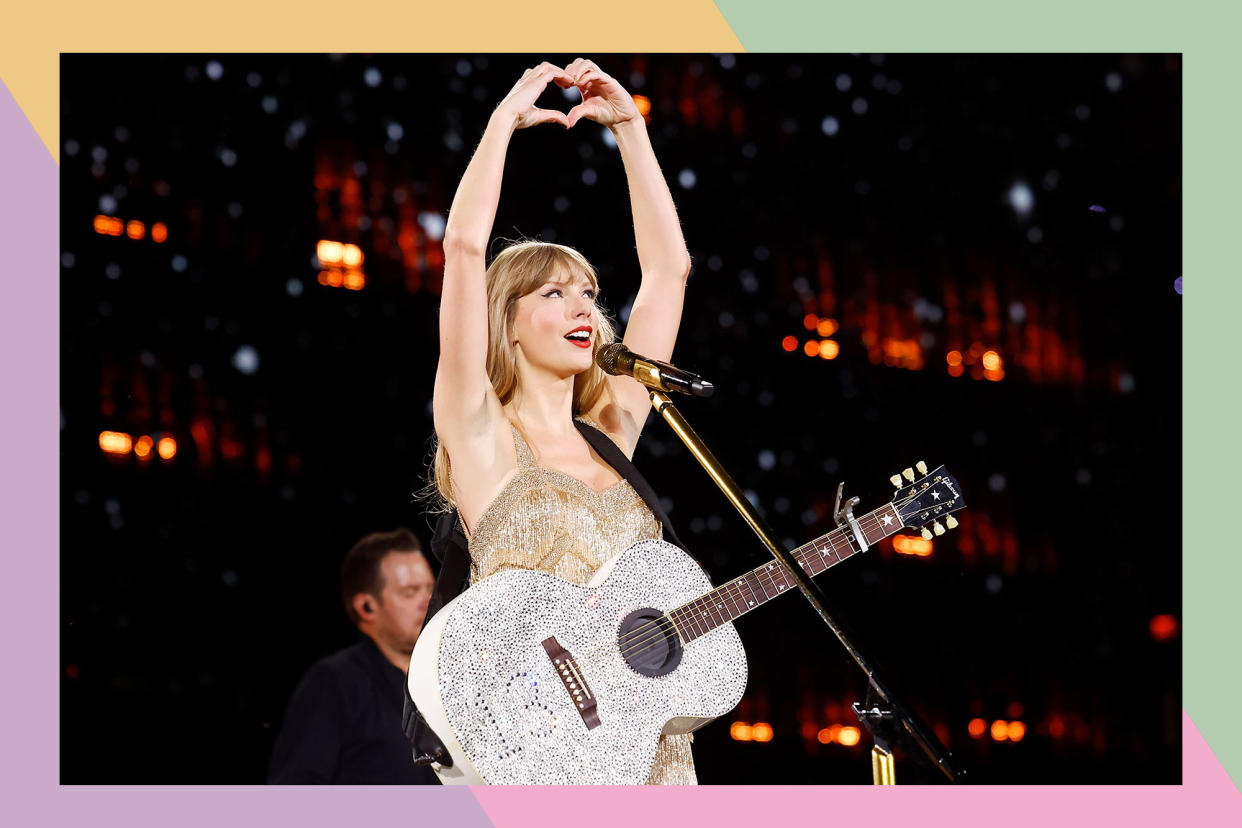Taylor Swift holding guitar and making heart hand gesture on the Eras Tour.